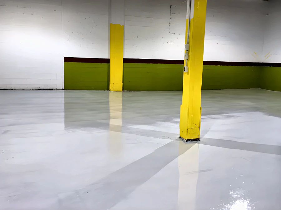 Light grey epoxy and urethane floor at the Adventure Den dog daycare in Vancouver, carried round the yellow columns to the green-painted walls