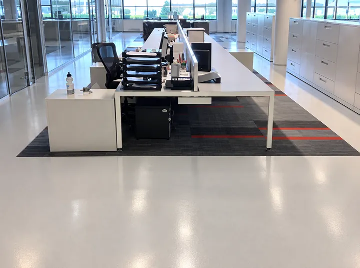 Light resinous office floor with carpet inset under a run of desks, Aritzia head office