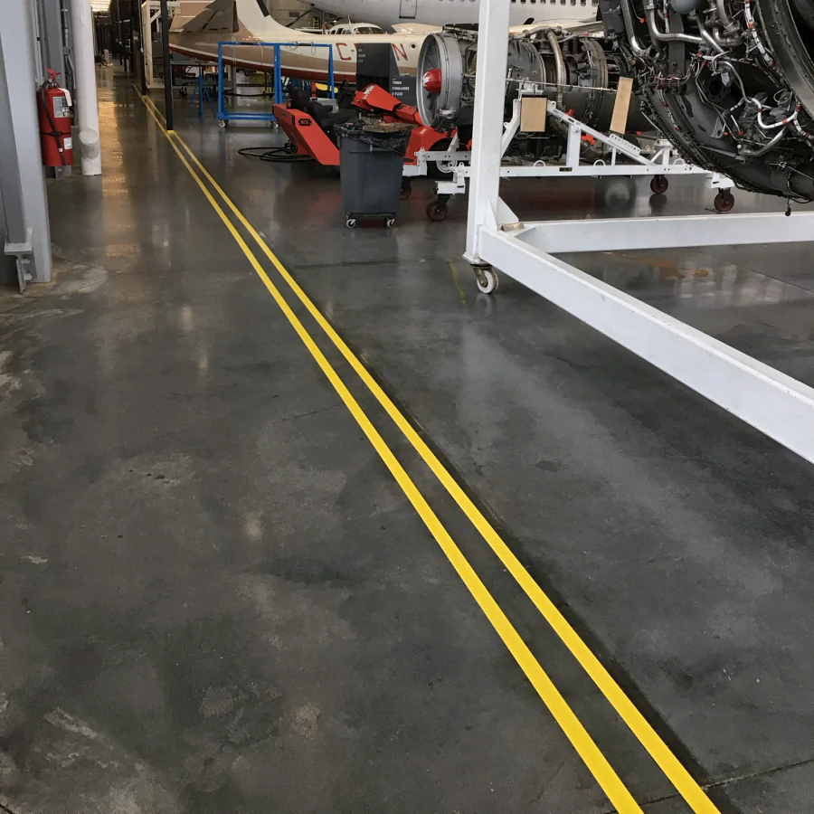 Double yellow urethane lines down the hangar walkway, past an engine on its stand