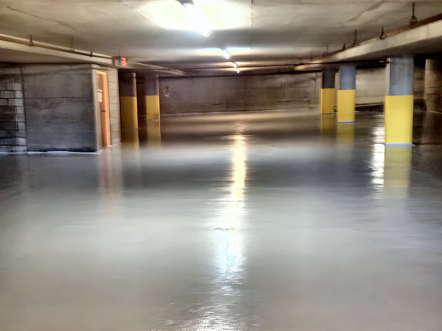 Light grey traffic coating across the drive aisle of a Beach Avenue parkade in Vancouver, with yellow column guards