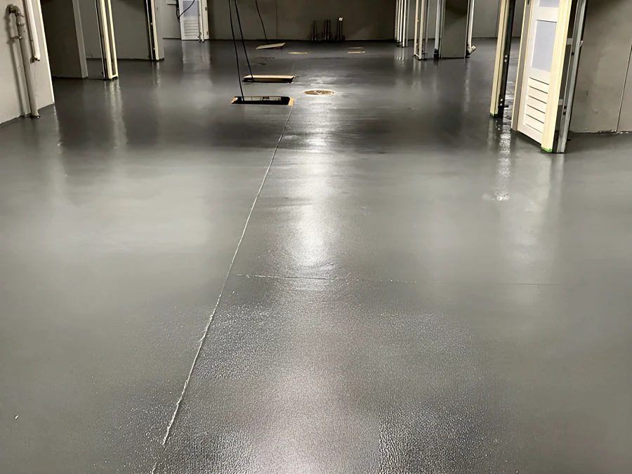 Grey traffic coating with a sheen across the Bellevue Avenue parking level, doors open along one wall