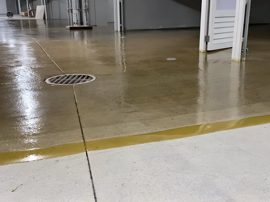 The first coat going across a parking level past a floor drain, the bare concrete still in front, 2289 Bellevue Avenue parkade