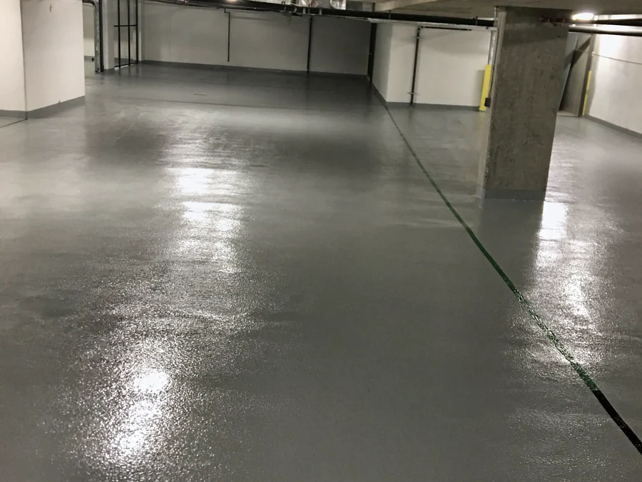 A finished drive aisle in a Brentwood parkade, Burnaby, the Tremco Vulkem coat turned up the walls as a grey base