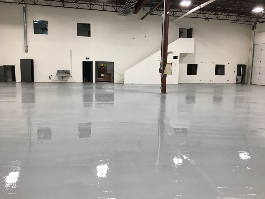 The finished epoxy and urethane warehouse floor in Burnaby, glossy light grey to the mezzanine stair, 2016
