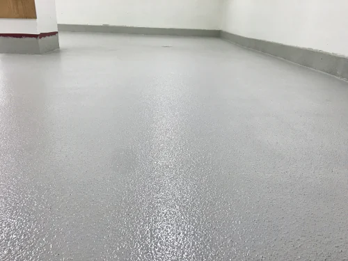 The light grey ResinTech EWS floor laid round the floor drain and coved up the walls of a commercial kitchen