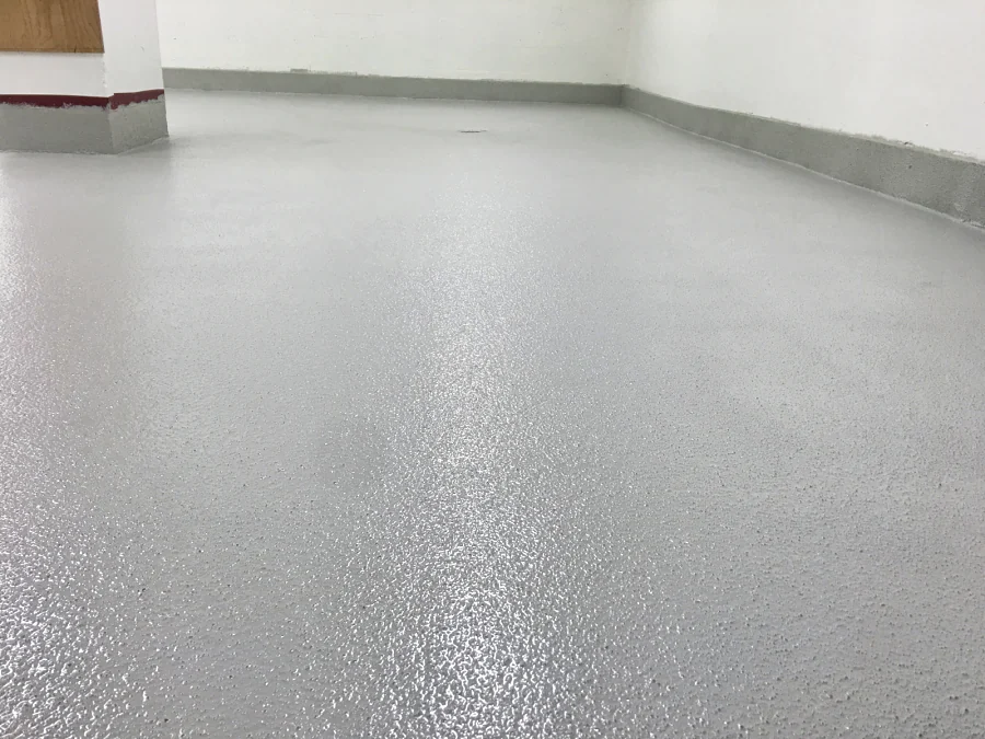 The light grey ResinTech EWS floor laid round the floor drain and coved up the walls of a commercial kitchen