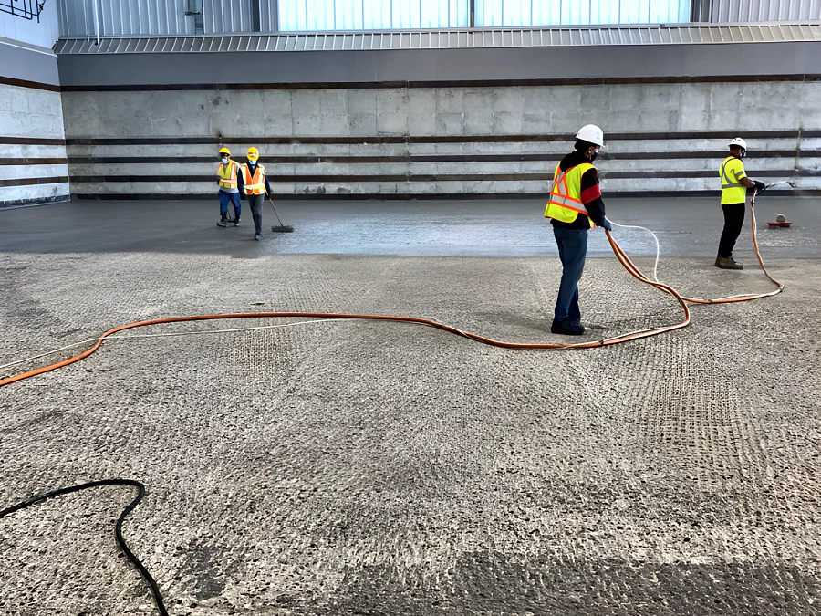 Crew applying Mapei Planibond EBA bonding agent across the slab of the new Coquitlam transfer station