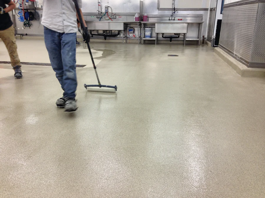 A crew member working the cementitious urethane out to the wall by squeegee at Costco Abbotsford