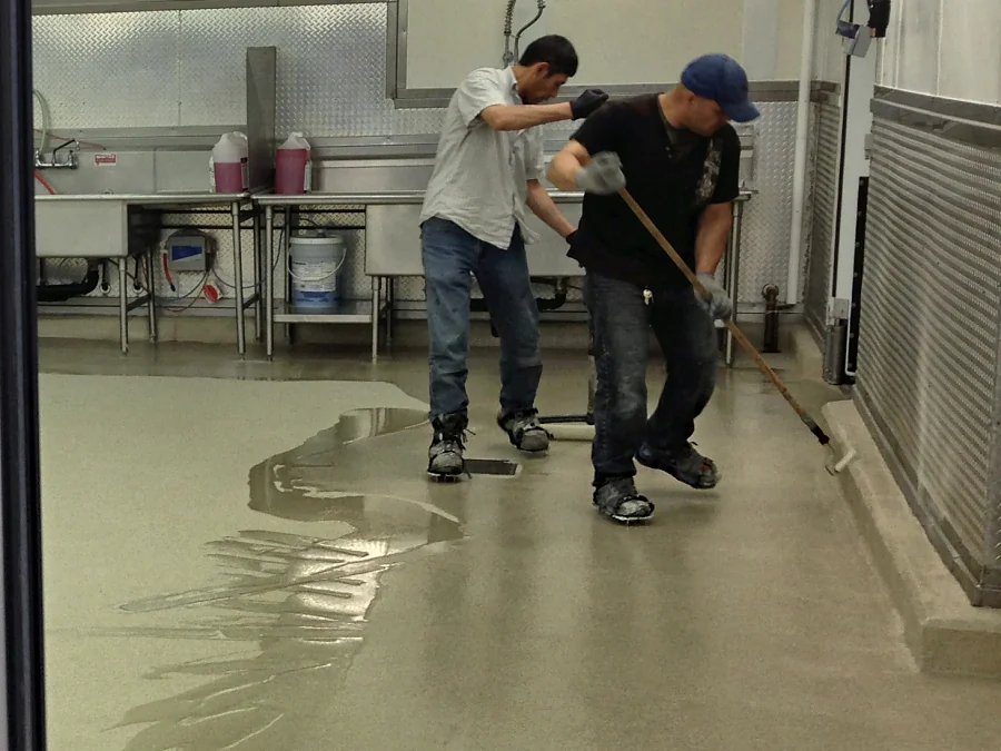 Two of the crew spreading the cementitious urethane by squeegee beside the sinks at Costco Abbotsford