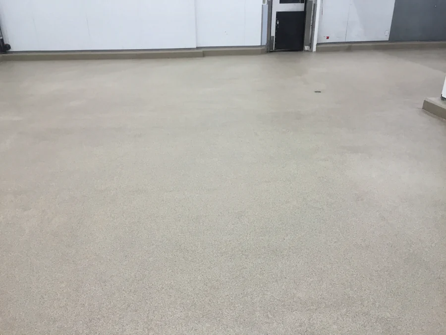 Finished decorative quartz floor through a back-of-house room at Costco Prince George, coved along the insulated-panel walls, with a floor drain