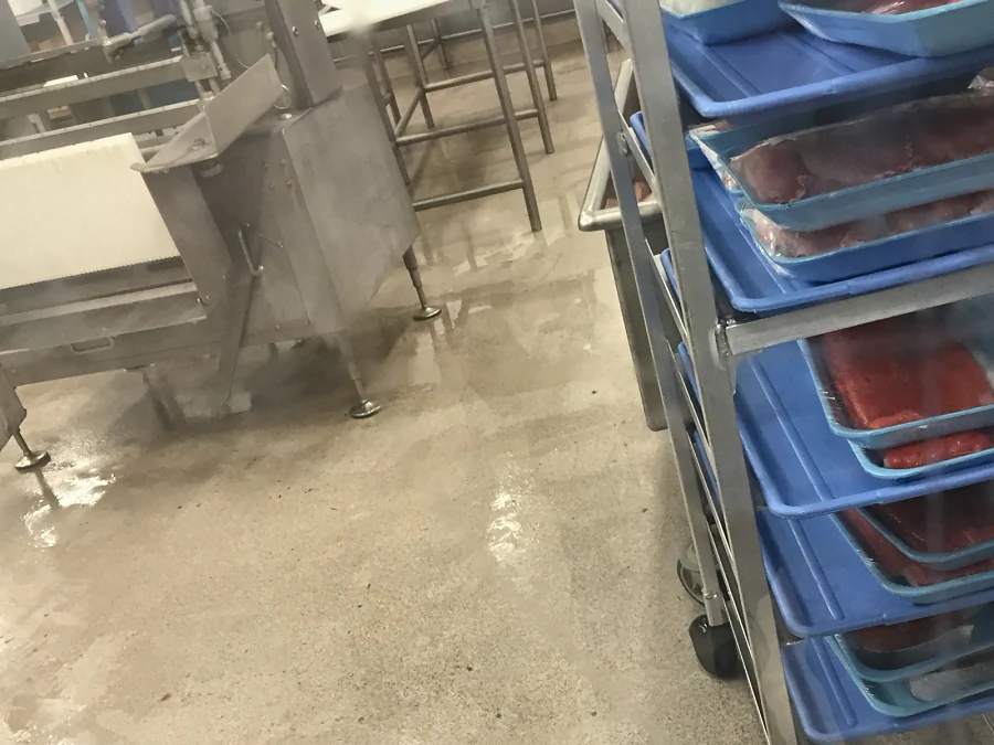 The decorative quartz floor in service in the meat room at Costco Prince George, seen through the viewing window, trays of meat on the racks