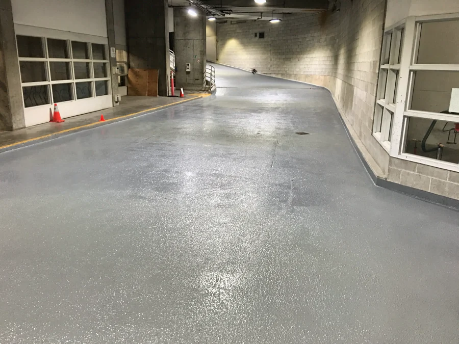 The lower ramp finished in a grey textured traffic coating, carried up the curb along the wall, 2016
