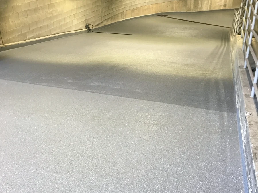 A traffic coating going down on the curve of a parkade ramp in Downtown Vancouver, the fresh coat darker where it is still wet