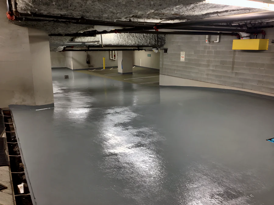 Freshly recoated grey traffic coating along the drive aisle of a Downtown Vancouver parkade, carried up the column and wall bases