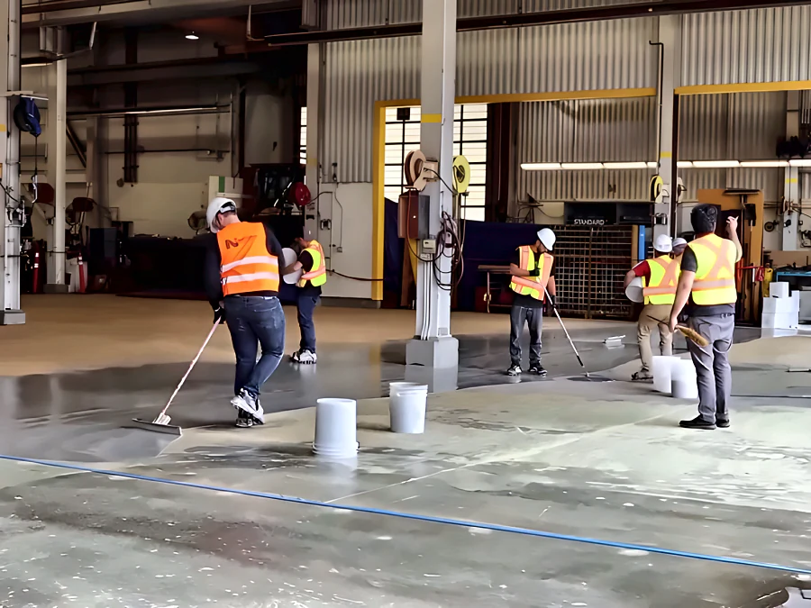 Crew in hi-vis installing ResinTech EWS across the floor of a Finning heavy-equipment workshop