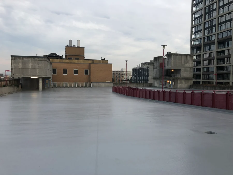 The parkade roof deck in Gastown, Vancouver, recoated in a grey Tremco Vulkem traffic coating along the railing to the stair tower