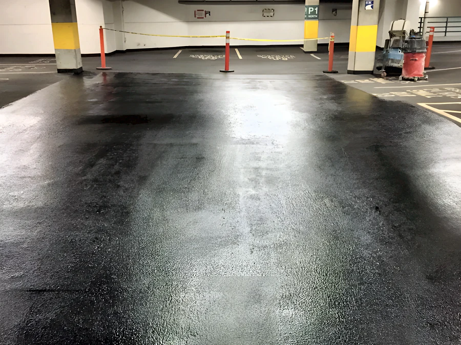 Glossy new traffic coating through a parking bay at the Vancouver RCPM/ICBC parkade, with yellow-banded columns behind