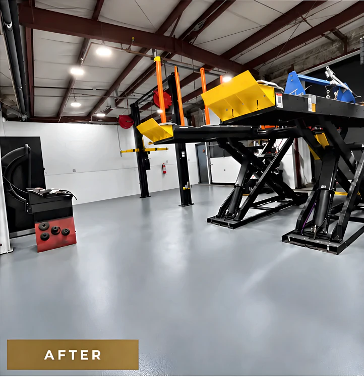 The same service bay after coating: a continuous light grey resinous floor under the scissor hoist