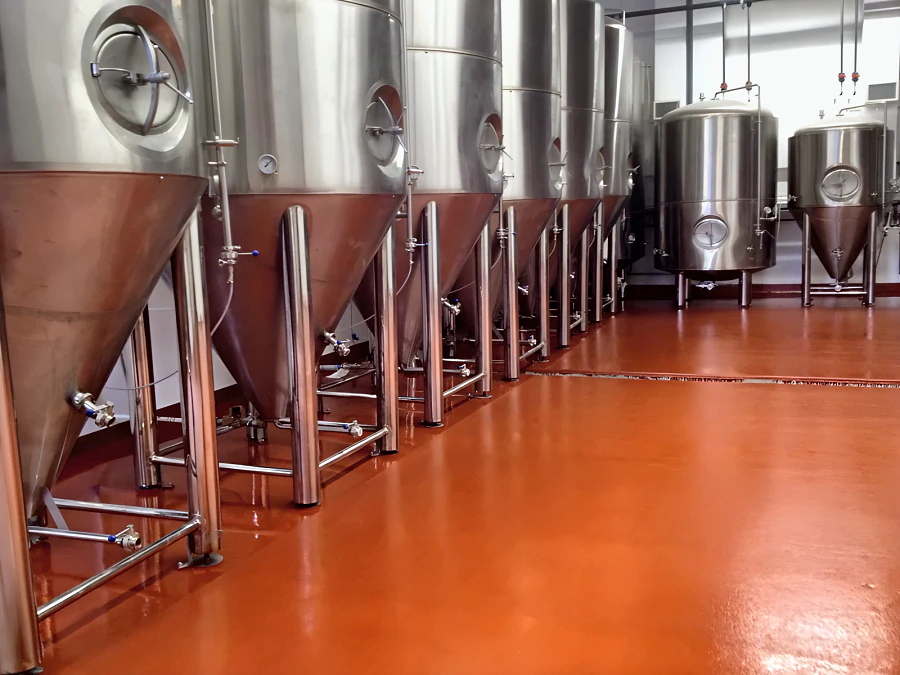 Red Eco Shop Floor under the row of stainless conical fermenters at Parallel 49 Brewing Company in East Vancouver, with a trench drain across the floor