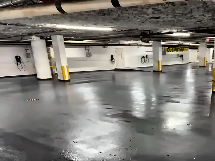 Glossy dark grey ResinTech TUE-FC across the Burnaby parkade slab on grade, with yellow column guards