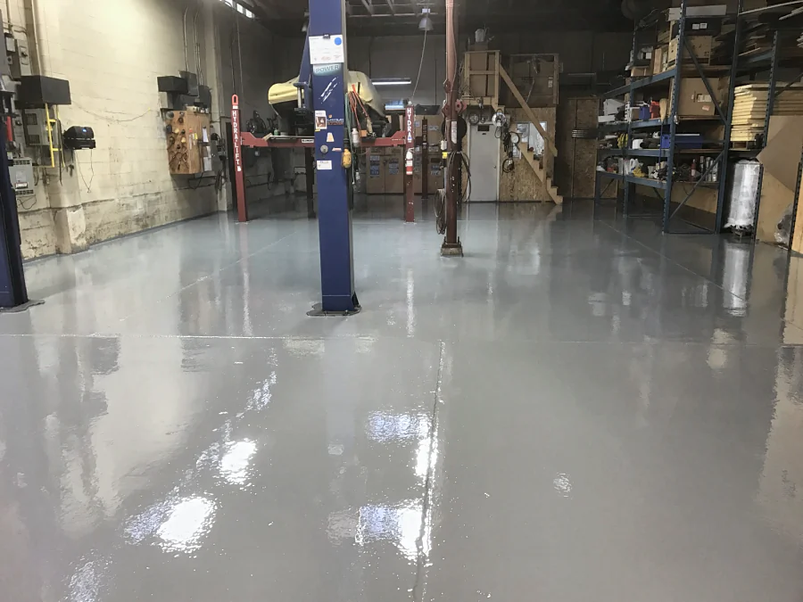 The finished floor across the same Richmond mechanic shop, glossy up to the racking and the wall