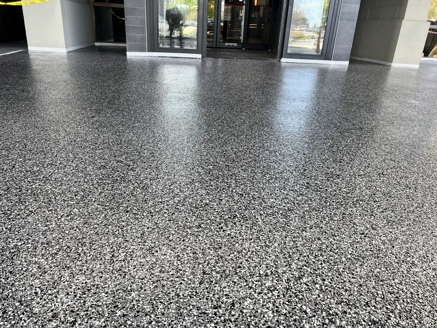 The ResinTech EWS flake floor across the covered front entrance, glossy up to the sliding doors