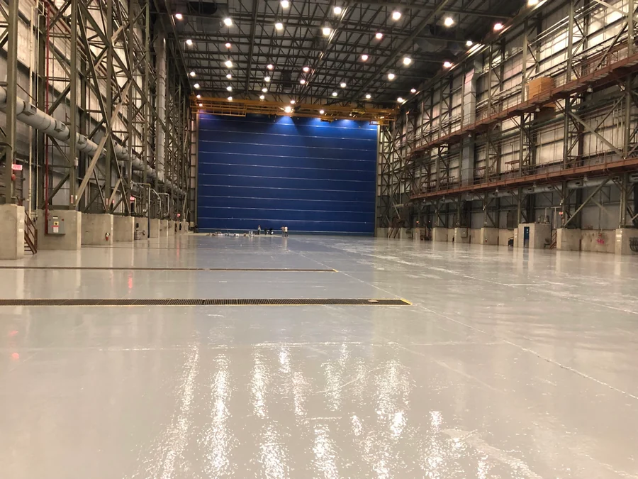 The finished grey epoxy floor the length of the hall to its full-height door