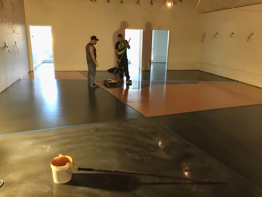 Showroom floor masked into diagonal sections with blue tape, charcoal coat down and the orange going on