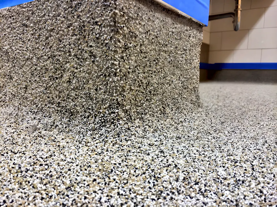 Close-up of the decorative quartz turned up a plinth as a coved base in a Surrey school washroom, the top edge still taped