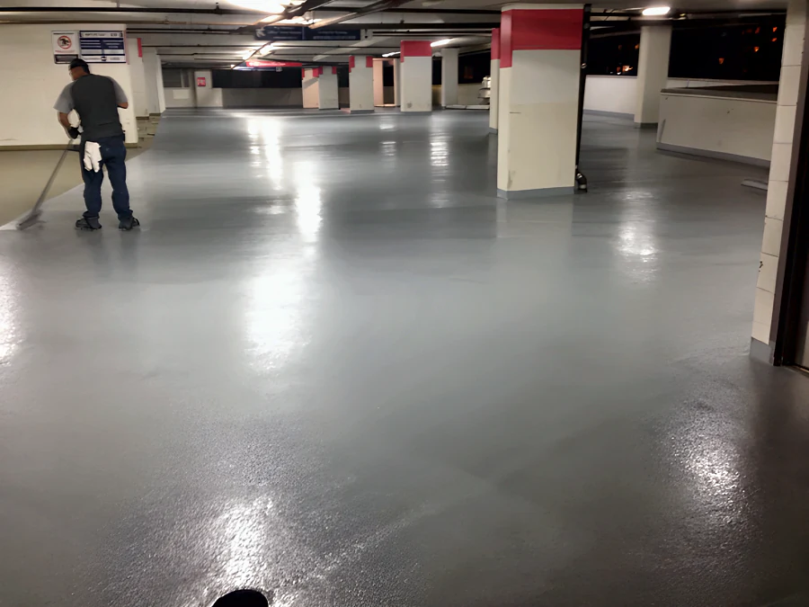 Freshly coated drive aisle and stalls in the Three West Centre parkade, Richmond, with the crew still working along the edge