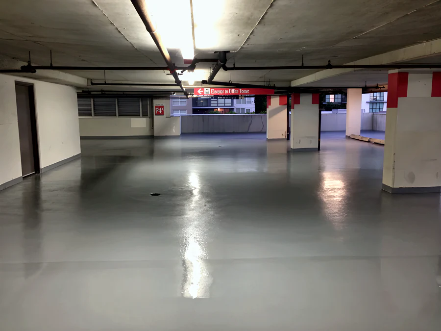 Fresh grey traffic coating across level P4A of the Three West Centre parkade in Richmond, with the red-banded columns and the Elevator to Office Tower sign