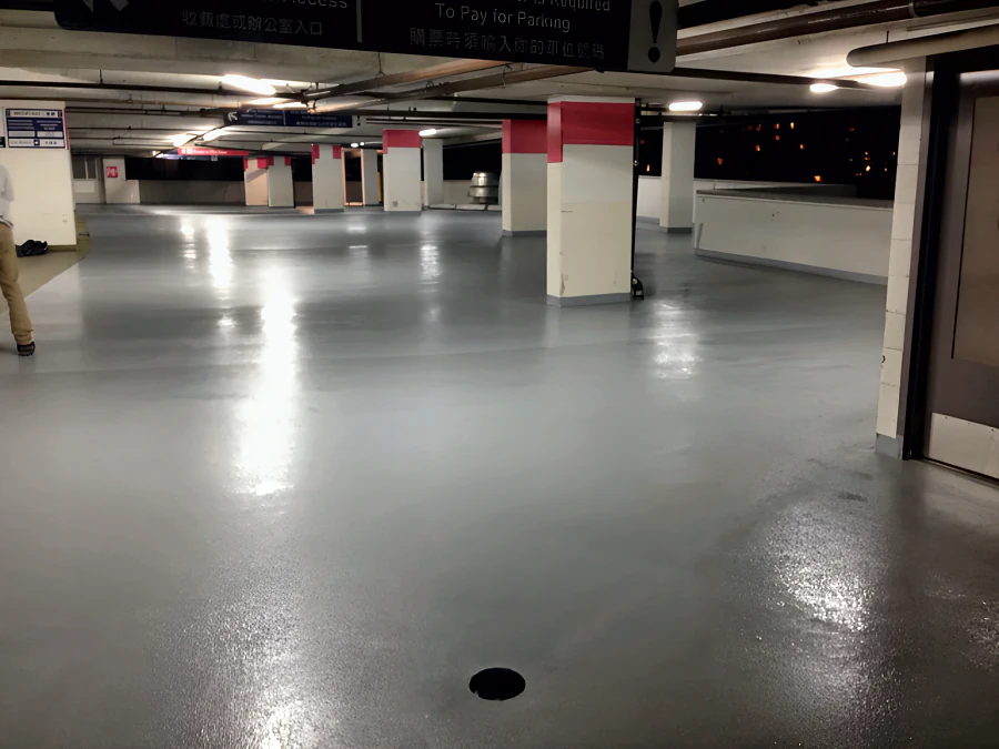 A finished level of the Three West Centre parkade in Richmond in grey traffic coating, round the floor drain and the red-banded columns