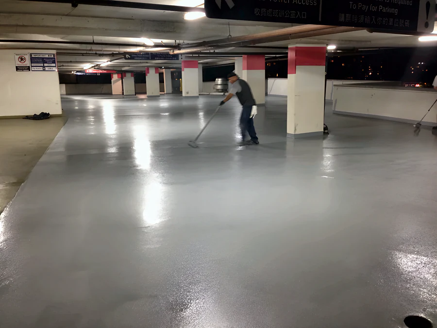 Crew rolling out a fresh grey traffic coating across a whole parking level of the Three West Centre parkade in Richmond