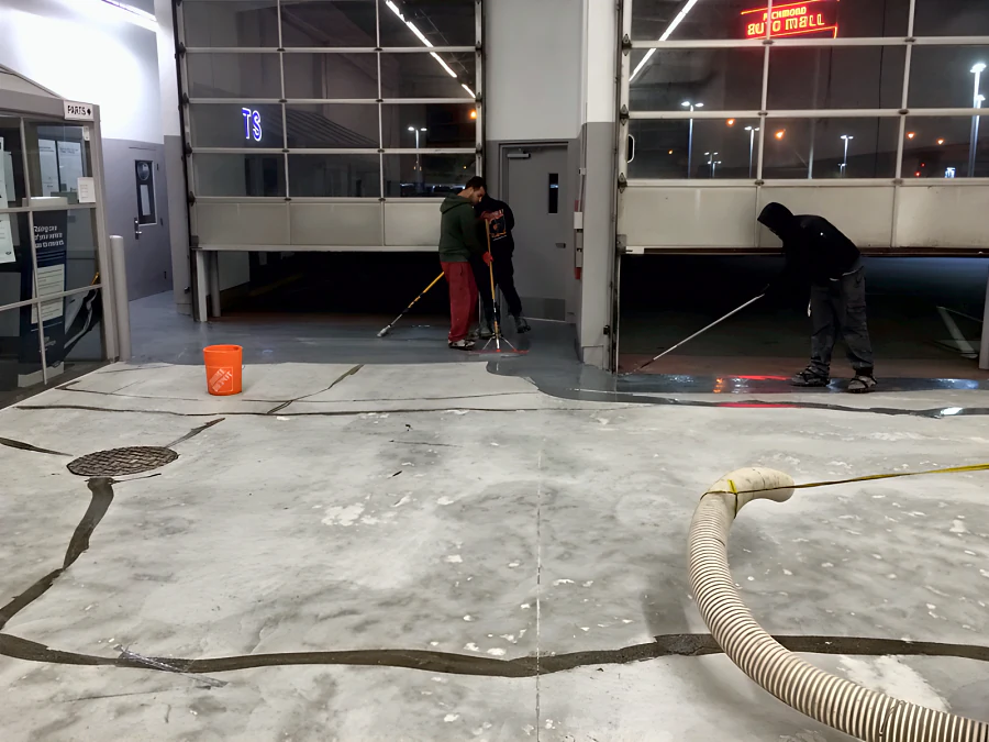 Crew laying the traffic coating at the roll-up doors of a Toyota dealership service drive at the Richmond Auto Mall, over a slab with its cracks filled
