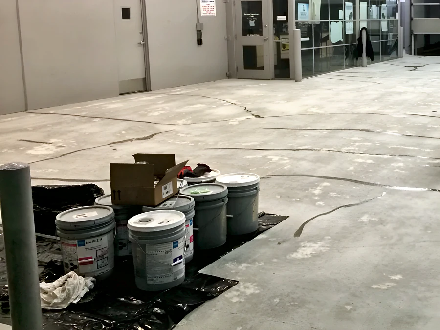 Cracks filled across the prepared concrete of the service drive at a Toyota dealership’s old shop in Vancouver, with the coating materials staged on plastic