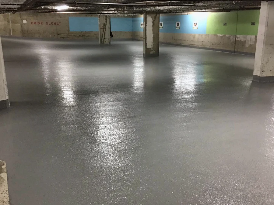 The finished grey Mapei traffic coating across the West Broadway parkade, the painted wall bands beyond