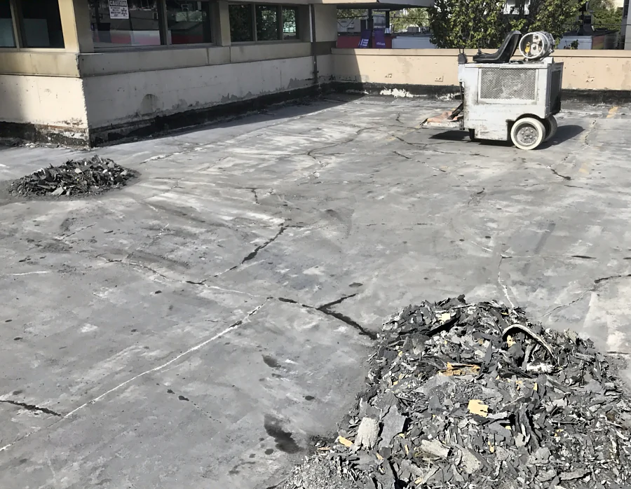 The old membrane scraped off an exterior parkade deck in Vancouver’s West End, the ride-on scraper and piles of removed membrane on the concrete
