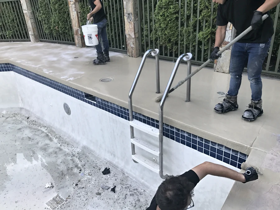 Crew rolling the new ResinTech coat to the tile line at the edge of a drained hotel pool in Whistler